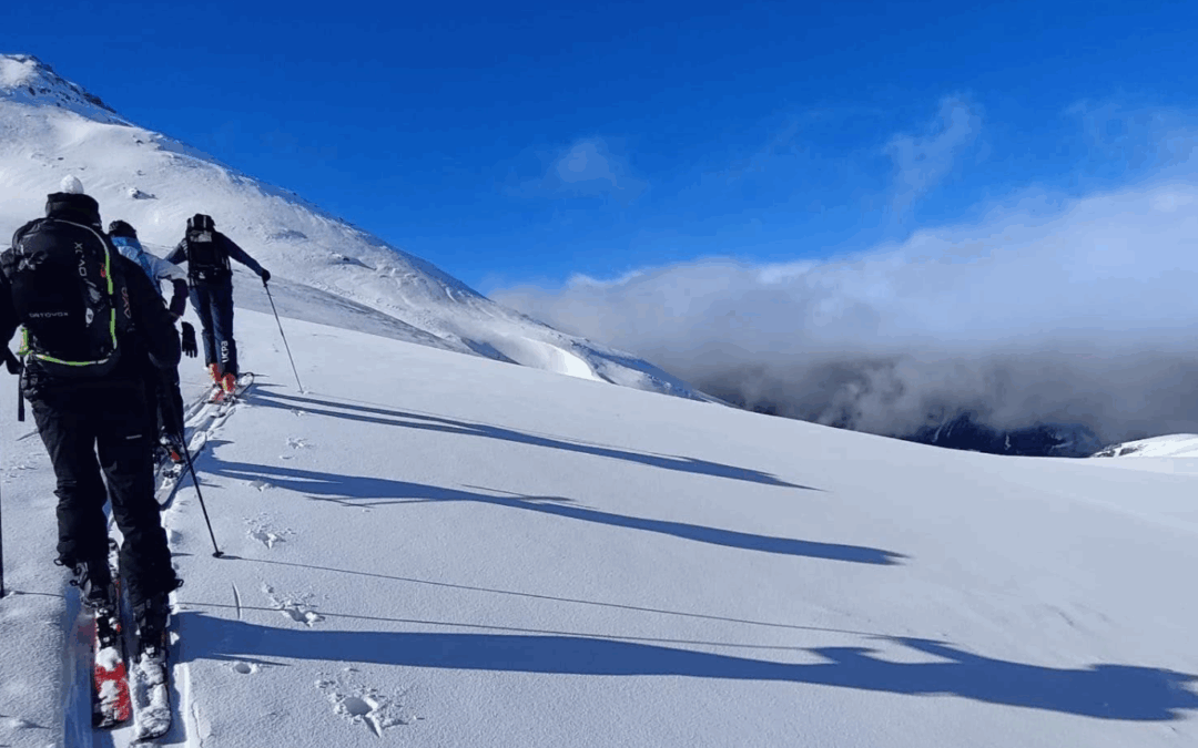 Skieurs de randonnée dans la neige poudreuse, ciel bleu et nuage de brouillard