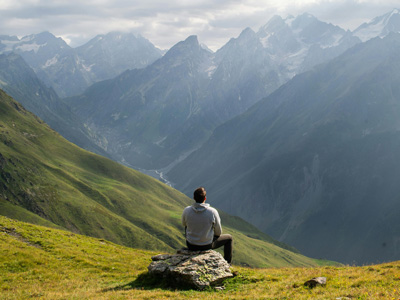 homme assis devant un paysage de montagne