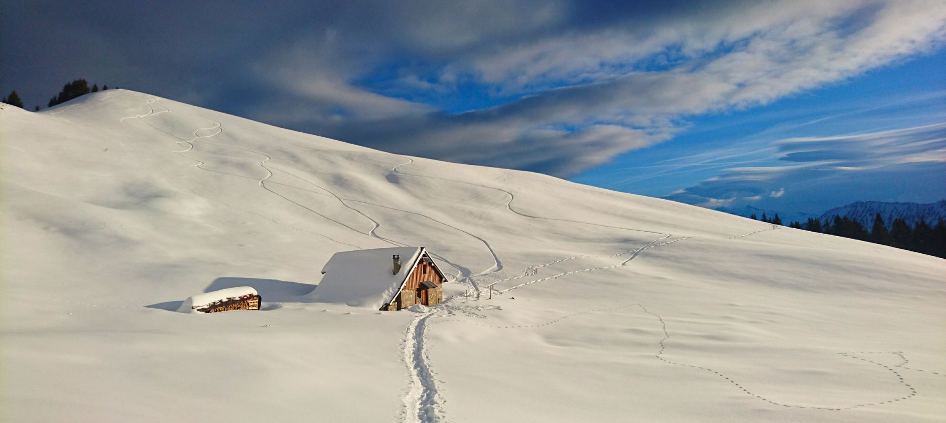 Randonnée raquette dans les Bauges Cabaner en hiver dans un paysage de montagne avec un ciel voilé et une trace de raquette dans la neige