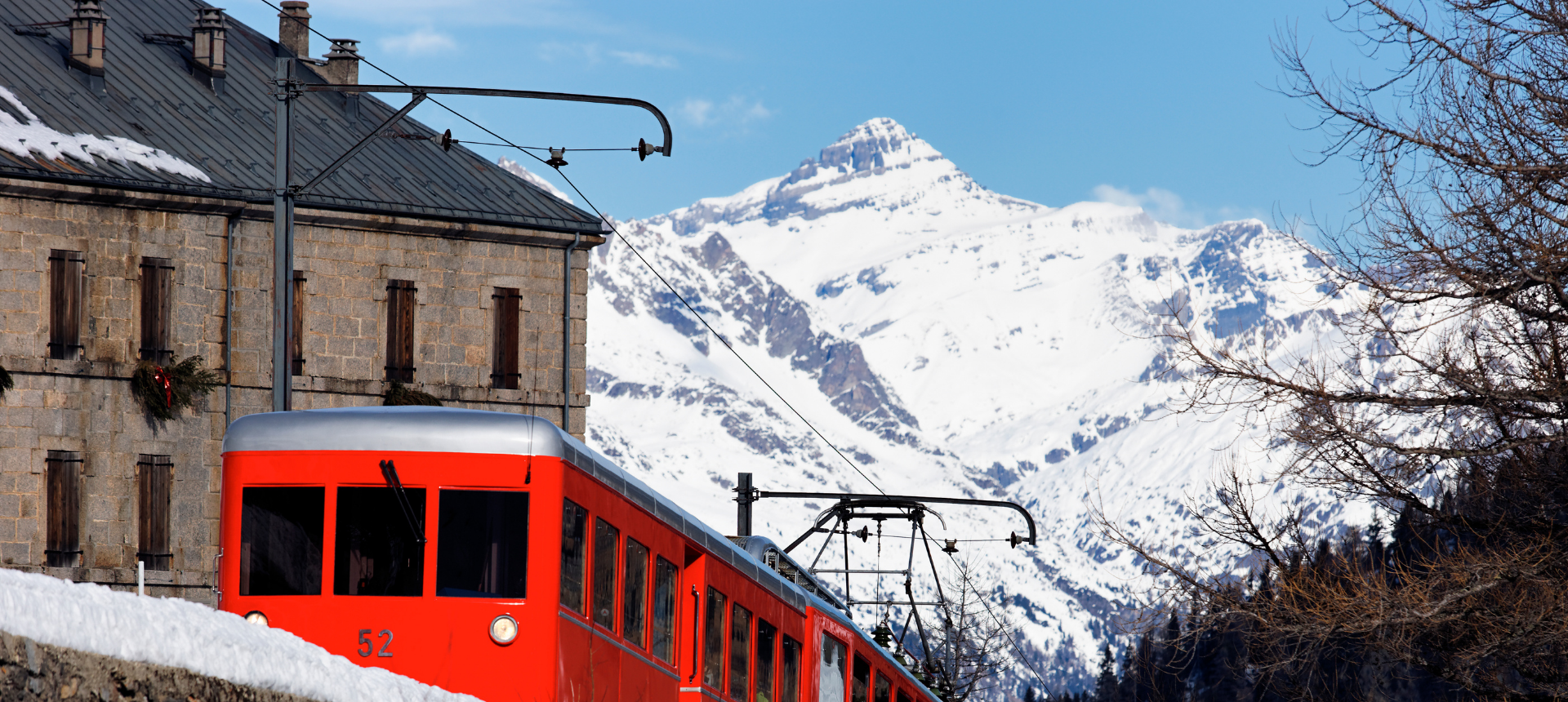 petit train rouge en face d'un sommet enneigé