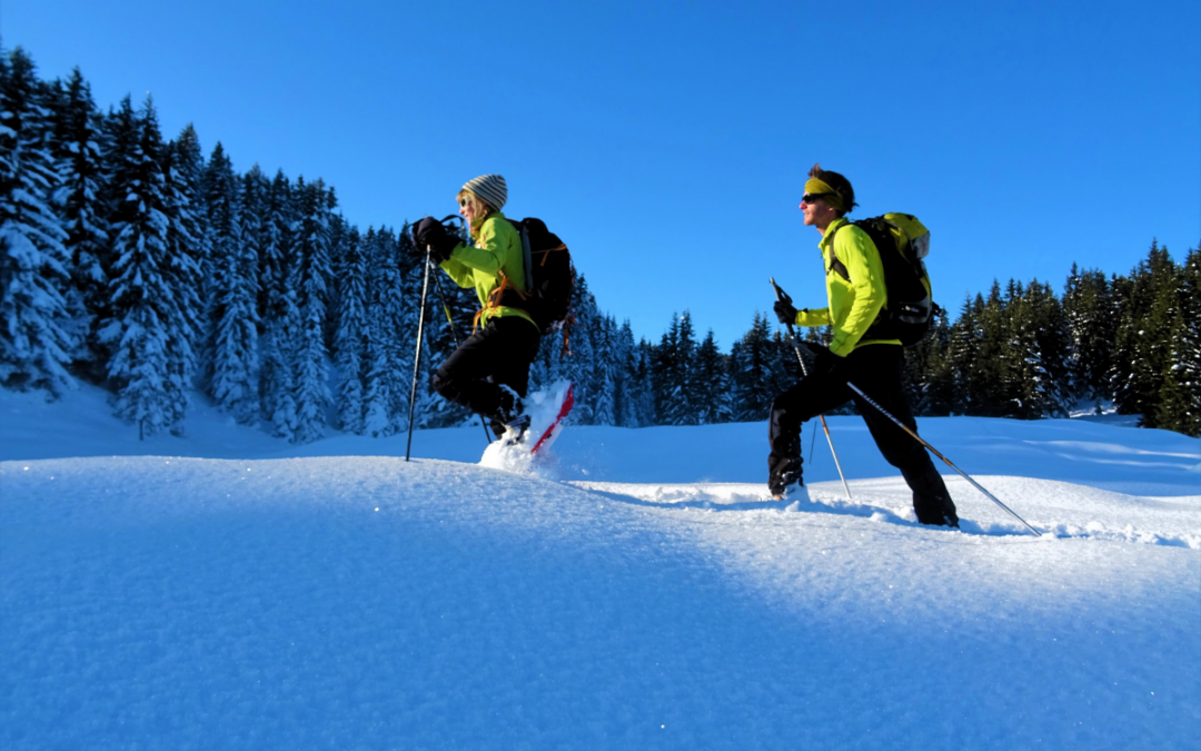 Deux randonneurs en raquettes progressent dans la neige profonde alors que le soleil se lève. Un belle journée s'annonce dans le Beaufortain