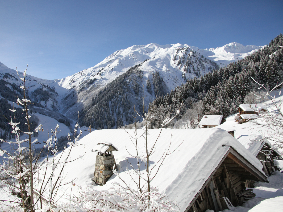 vue sur les montagnes du Beaufortain depuis des chalets aux toits bien chargés en neige